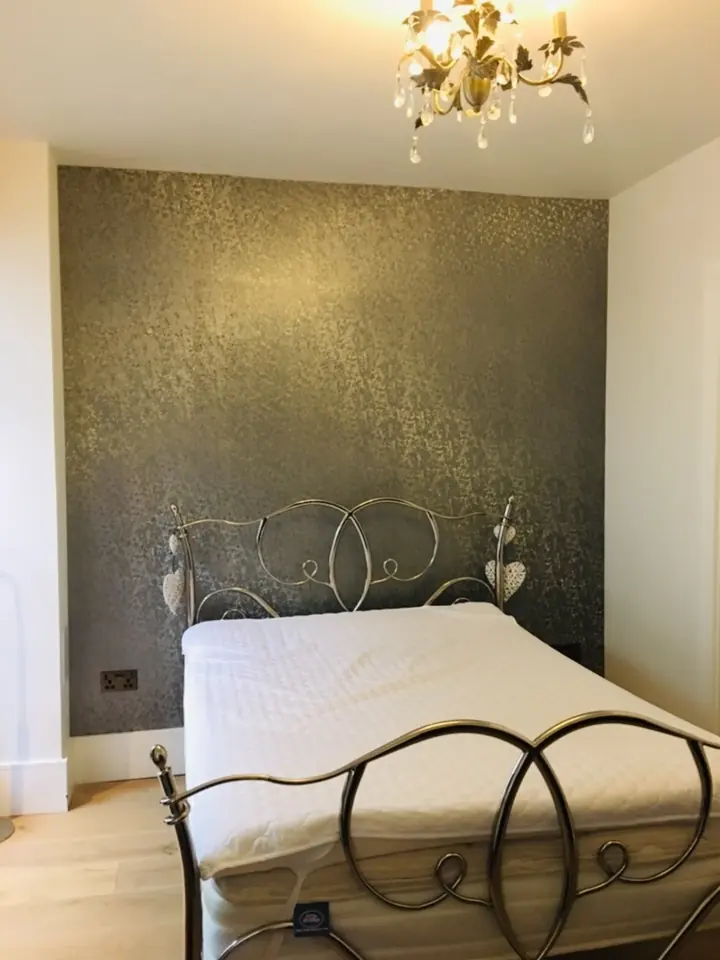 Damask wallpaper detail in a finished bedroom with soft neutral bedding