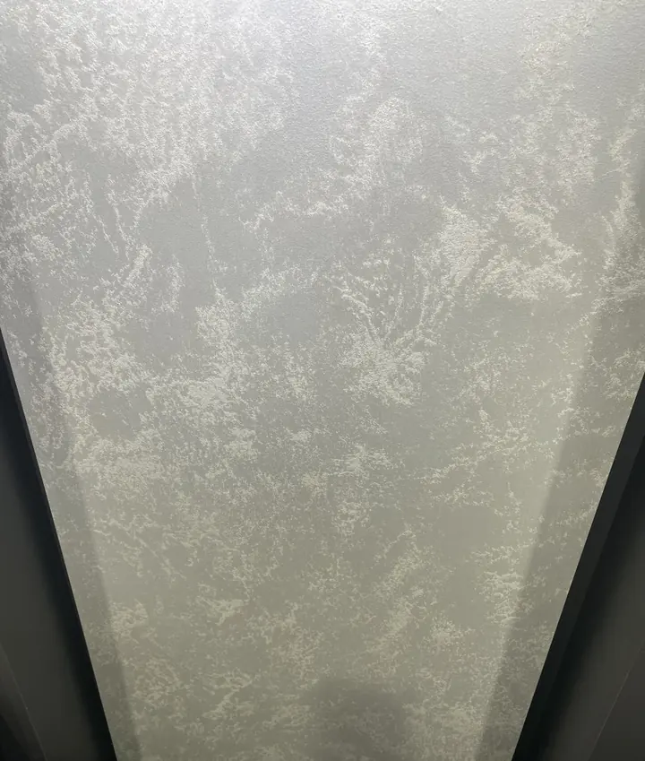 Close-up of a pale polished plaster wall showing a layered reflective texture
