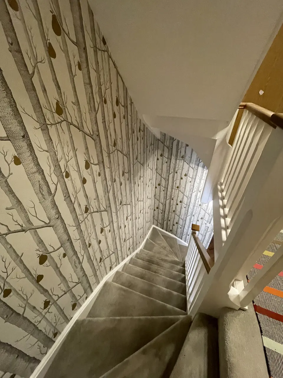 Muswell Hill entrance stairwell hung with bold Hicks Hexagon wallpaper across walls and stair rise in-progress view