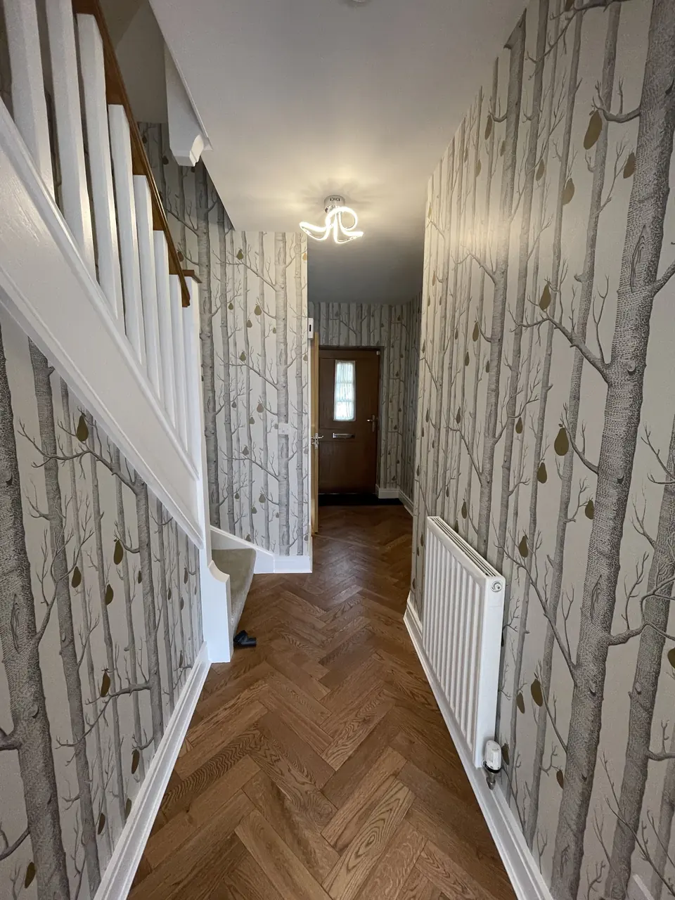 Muswell Hill entrance stairwell hung with bold Hicks Hexagon wallpaper across walls and stair rise close detail