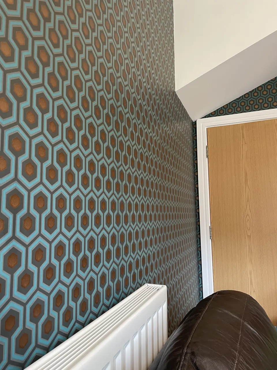 Muswell Hill entrance stairwell hung with bold Hicks Hexagon wallpaper across walls and stair rise